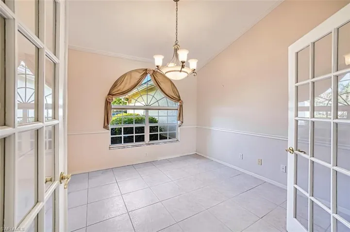 Den with a chandelier, crown molding, light tile patterned floors, and french doors