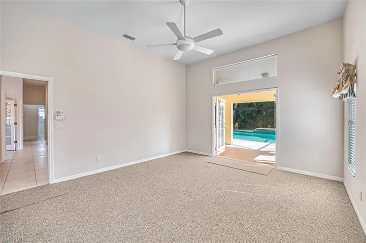Empty room with light carpet, a ceiling fan, and healthy amount of natural light