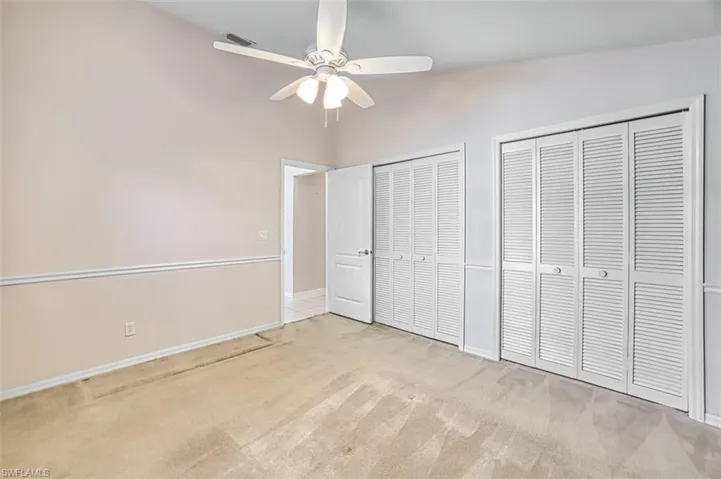 Unfurnished bedroom featuring two closets, carpet flooring, and a ceiling fan
