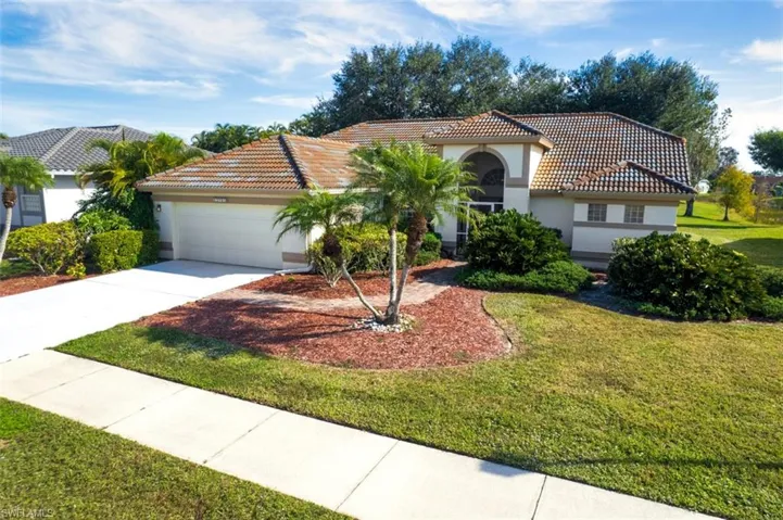 Mediterranean / spanish home with a tile roof, stucco siding, driveway, an attached garage, and a front yard