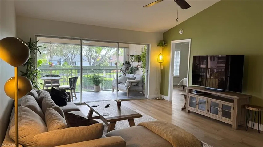 Living room featuring light wood-type flooring, ceiling fan, and lofted ceiling