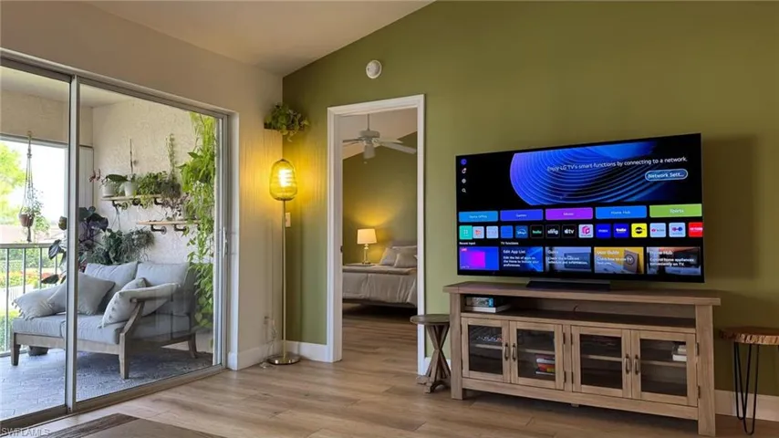 Living room with ceiling fan, hardwood / wood-style floors, and vaulted ceiling