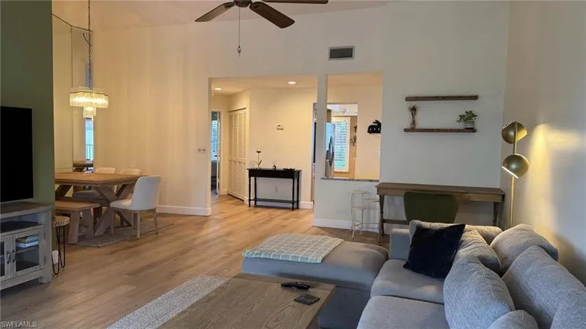 Living room featuring ceiling fan, a high ceiling, and light hardwood / wood-style flooring