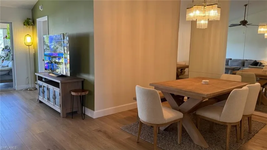 Dining room featuring ceiling fan with notable chandelier, light wood-type flooring, and lofted ceiling