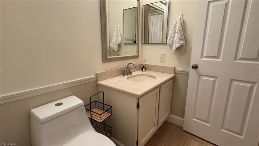 Bathroom with hardwood / wood-style floors, vanity, and toilet