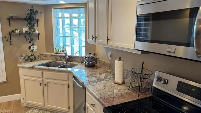 Kitchen with sink, white cabinets, stainless steel appliances, and light hardwood / wood-style flooring