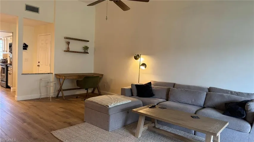Living room featuring wood-type flooring, ceiling fan, and a high ceiling