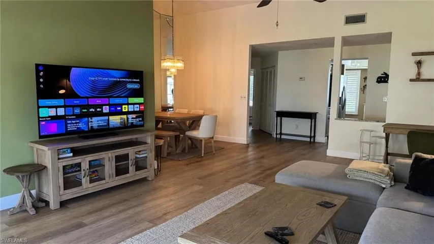 Living room with hardwood / wood-style flooring, ceiling fan with notable chandelier, and a healthy amount of sunlight