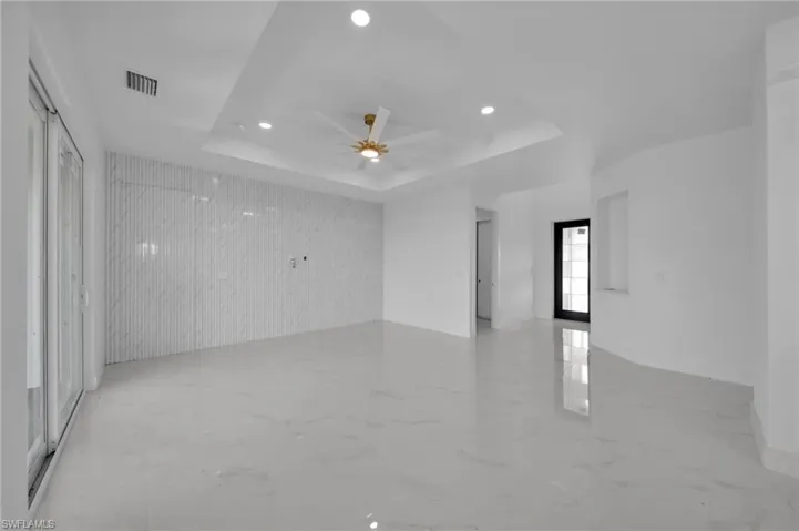 Spare room featuring light marble finish floors, recessed lighting, a tray ceiling, an accent wall, and a ceiling fan