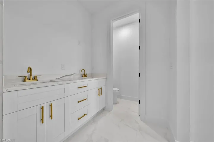 Bathroom featuring double vanity and light marble finish floors