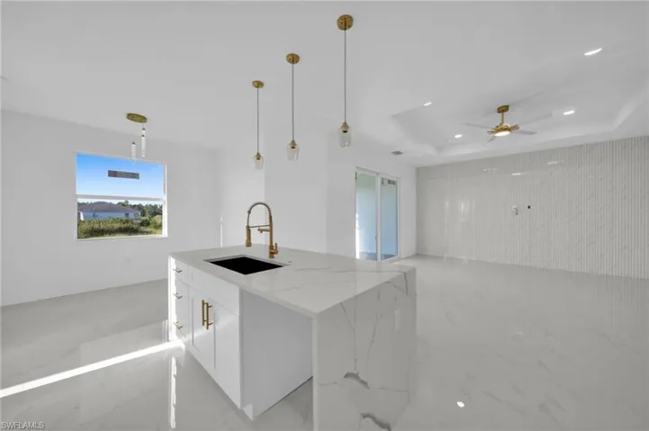 Kitchen with white cabinetry, light marble finish floors, light stone countertops, a raised ceiling, and recessed lighting