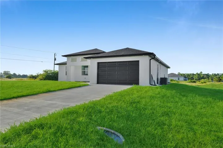 View of front of home featuring concrete driveway, stucco siding, a front yard, and a garage