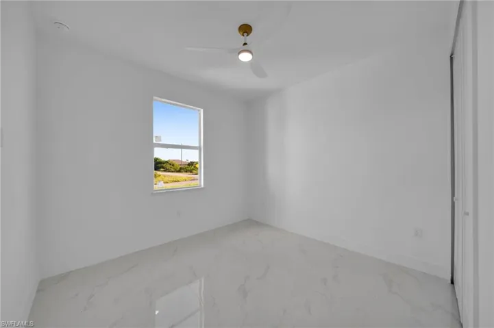 Unfurnished room featuring light marble finish floors and a ceiling fan