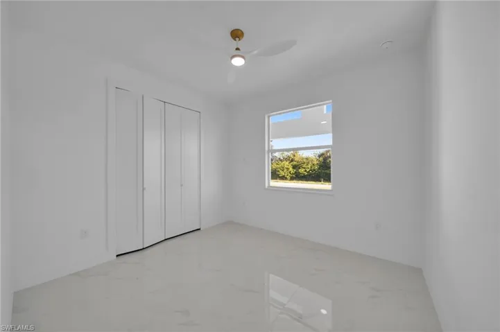 Unfurnished bedroom with light marble finish floors, a ceiling fan, and a closet