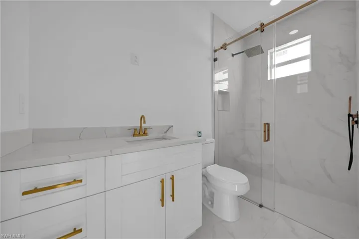 Full bath featuring vanity, light marble finish floors, and a marble finish shower