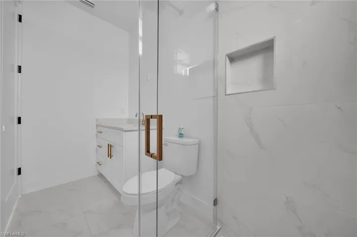 Bathroom with vanity, light marble finish floors, and a shower stall