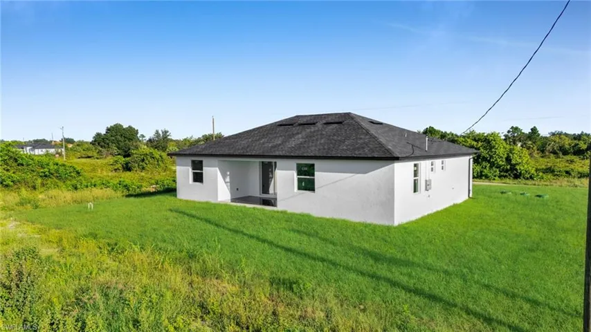 Back of property featuring stucco siding, a patio, a yard, and a shingled roof