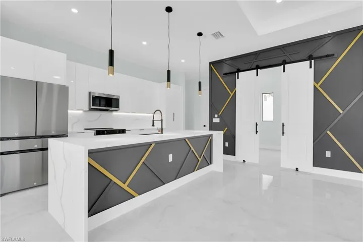 Kitchen featuring stainless steel appliances, white cabinetry, a barn door, modern cabinets, and pendant lighting