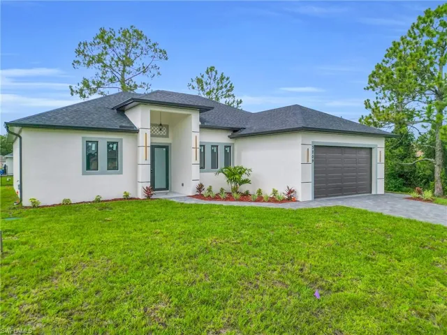 Prairie-style home featuring an attached garage, driveway, a shingled roof, and stucco siding