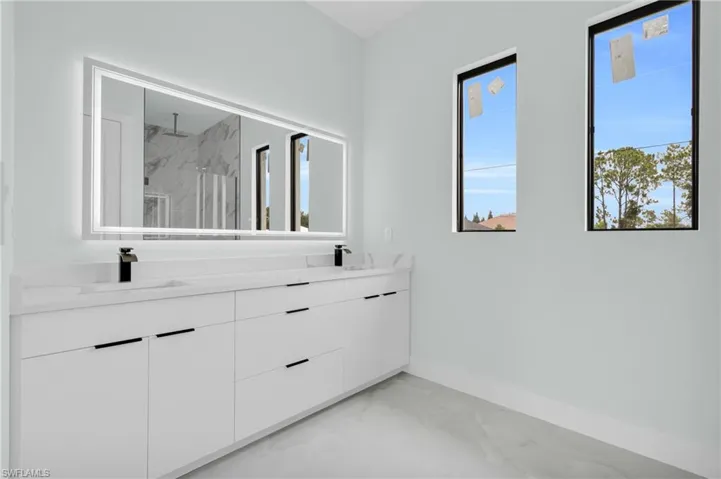 Bathroom with marble finish floors, a marble finish shower, and double vanity