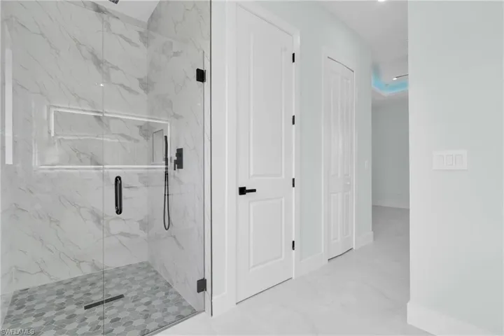 Bathroom with a marble finish shower and marble finish flooring