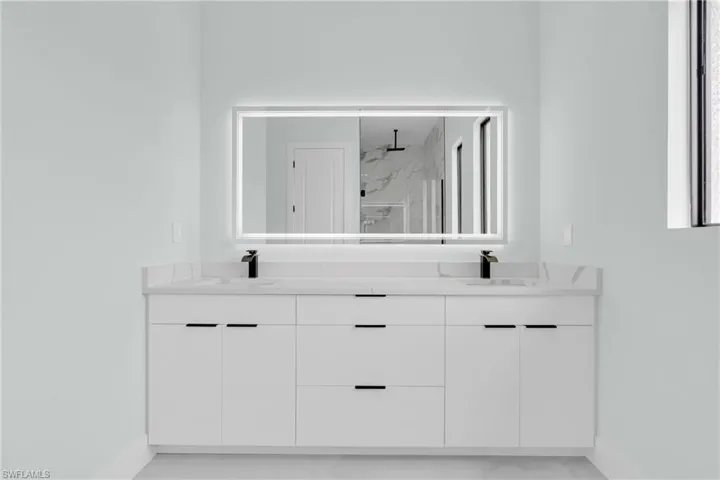 Full bath with double vanity, a marble finish shower, and marble look tile flooring