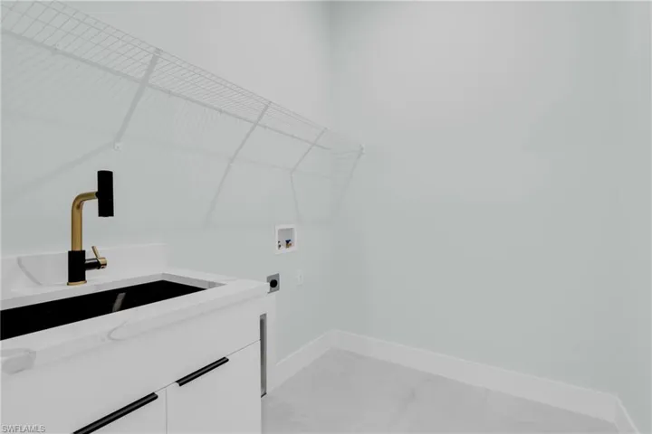 Washroom featuring hookup for an electric dryer, washer hookup, cabinet space, and light marble finish floors