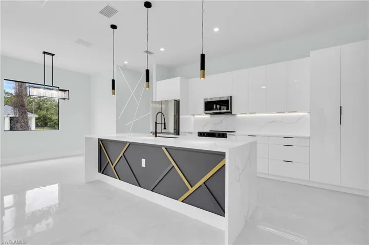 Kitchen featuring stainless steel microwave, modern cabinets, light marble finish flooring, white cabinets, and recessed lighting