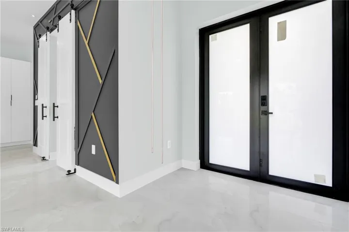 Entrance foyer featuring french doors, light marble finish flooring, and a barn door