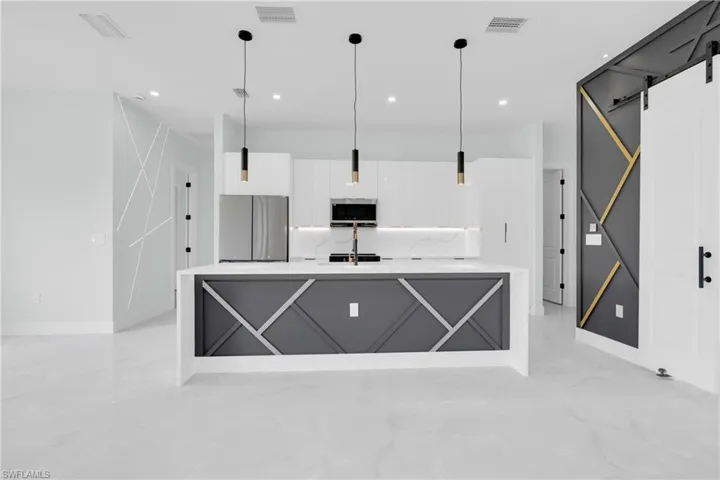 Kitchen featuring appliances with stainless steel finishes, white cabinets, modern cabinets, light marble finish floors, and light countertops