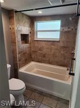 Bathroom with tile patterned floors, toilet, and tiled shower / bath combo