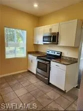 Kitchen with stainless steel appliances, dark tile patterned floors, and white cabinets