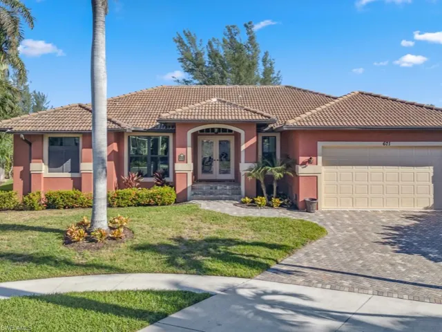 View of front of property with a front yard, french doors, and a garage