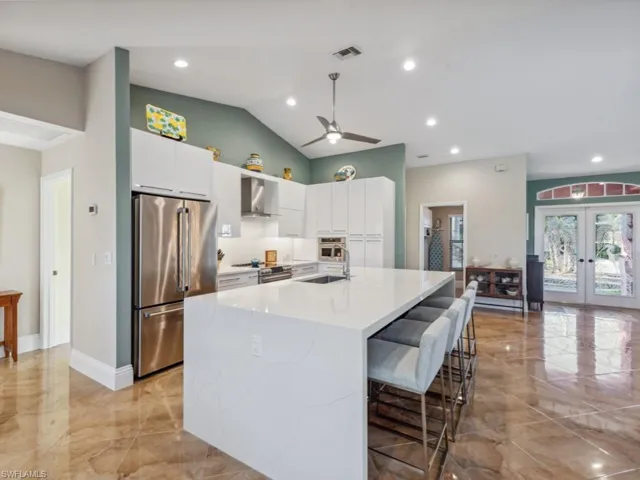 Kitchen with french doors, white cabinets, stainless steel appliances, and wall chimney range hood