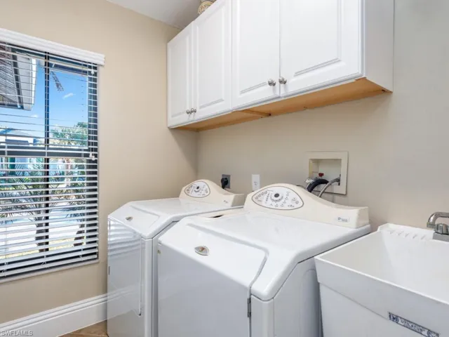 Clothes washing area with tile patterned floors, sink, cabinets, and independent washer and dryer