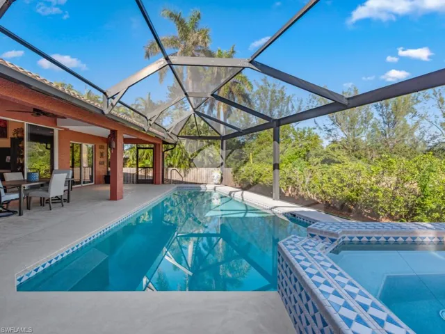 View of swimming pool featuring a patio, glass enclosure, and ceiling fan