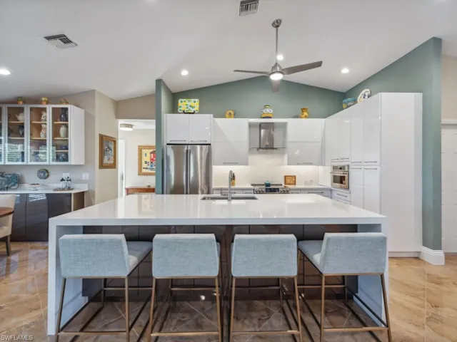 Kitchen featuring an island with sink, sink, appliances with stainless steel finishes, and a breakfast bar area