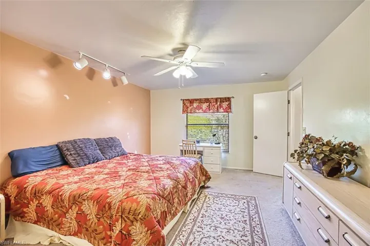 Bedroom with track lighting, light colored carpet, and ceiling fan