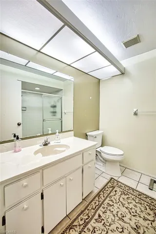Bathroom with vanity, a stall shower, light tile patterned floors, and a textured ceiling