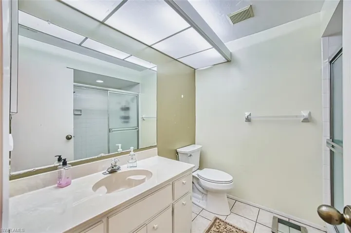 Bathroom with light tile patterned flooring, vanity, and a shower stall