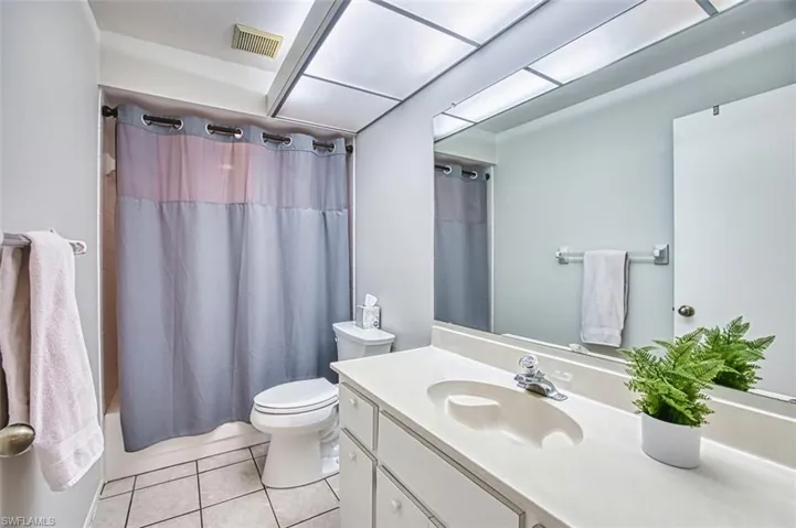 Bathroom with shower / bath combination with curtain, vanity, and light tile patterned flooring