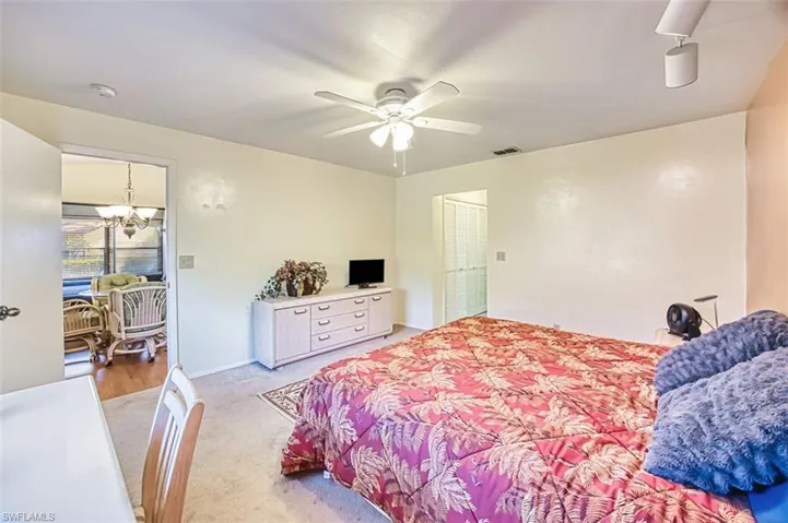 Bedroom with light carpet, a chandelier, and a ceiling fan