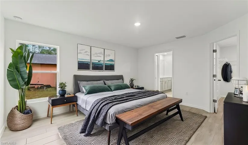 Bedroom with light wood-style floors, ensuite bath, and a spacious closet