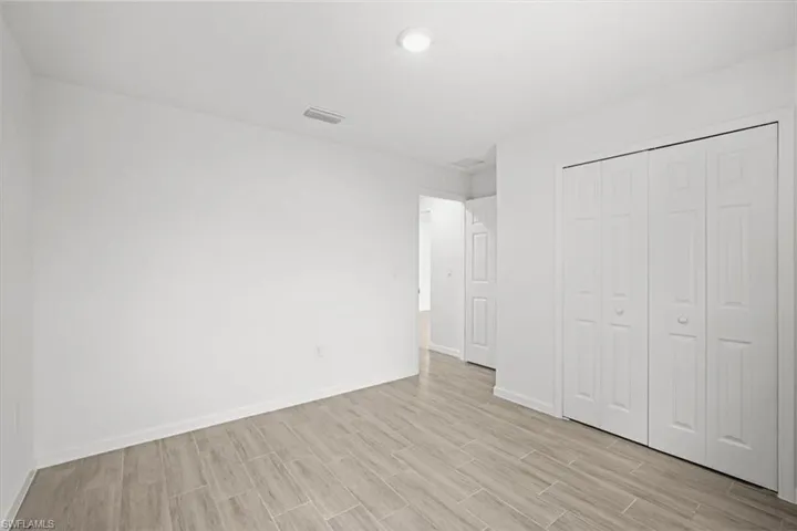 Unfurnished bedroom with wood finish floors and a closet