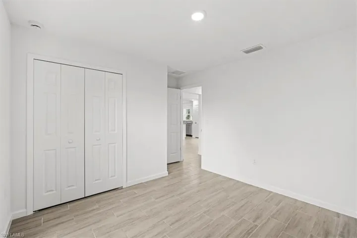 Unfurnished bedroom featuring wood finish floors, a closet, and recessed lighting