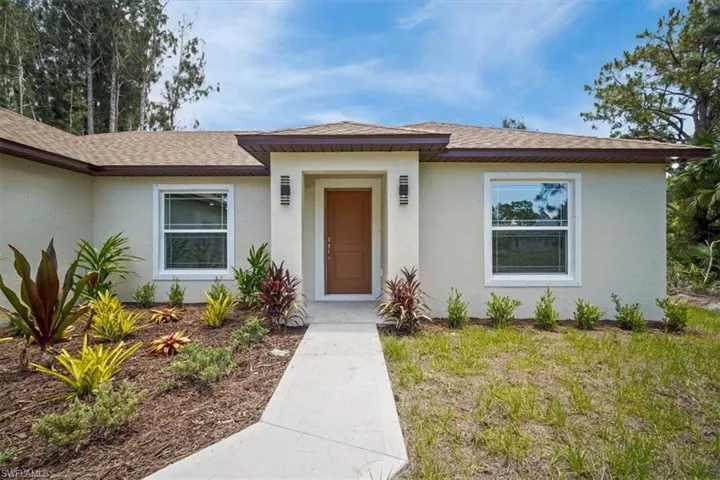 Doorway to property with roof with shingles and stucco siding