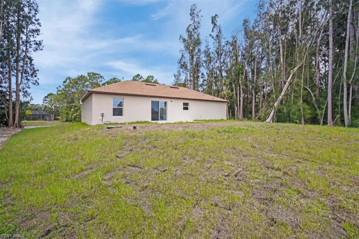 Back of property with a lawn and stucco siding