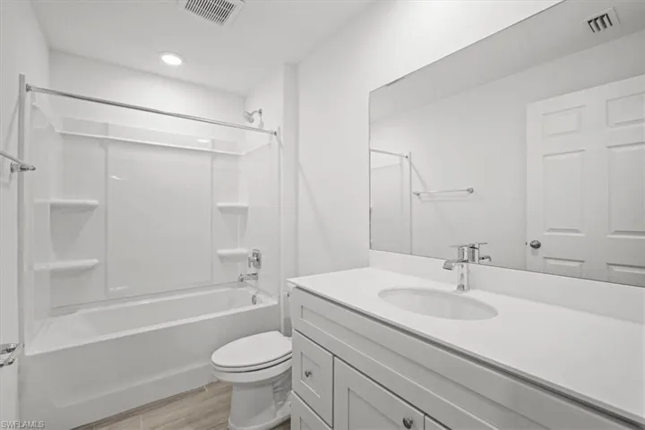 Bathroom with vanity, tub / shower combination, and light wood-style flooring