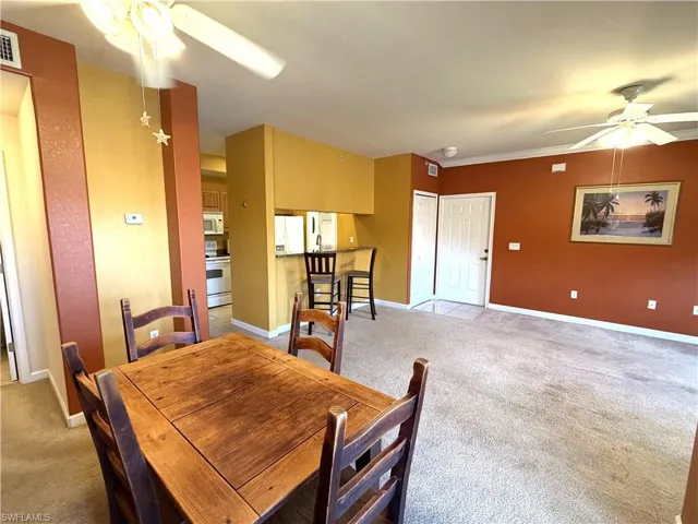 Ceiling fan with light, carpet, and dining room table