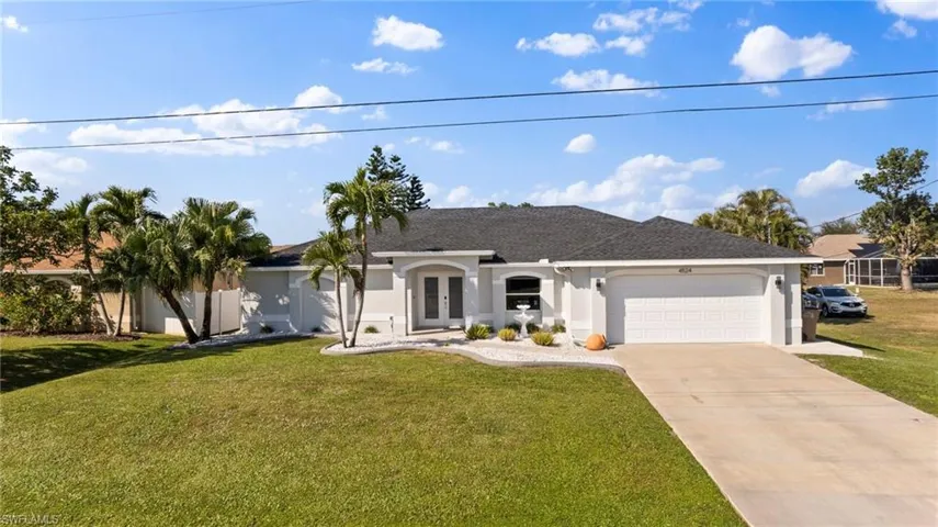 Ranch-style home with stucco siding, french doors, a garage, a front lawn, and driveway